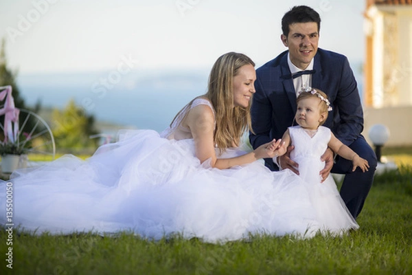 Obraz Summer wedding with children. Happy bride and groom in wedding day with little daughter.
