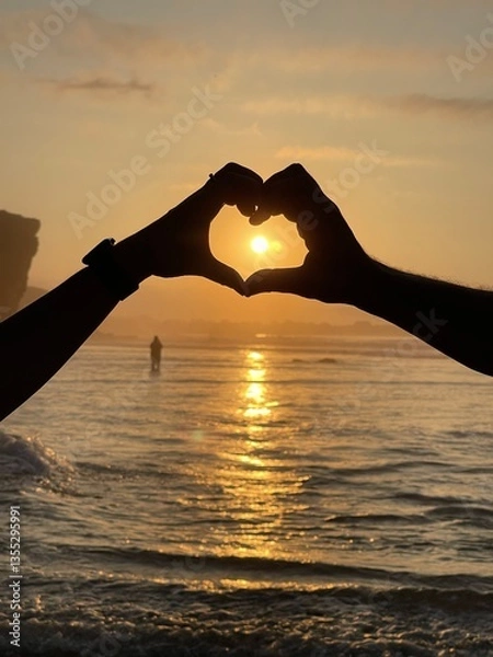 Fototapeta Silhouette of a heart holding hands at sunset on the beach. Vertical