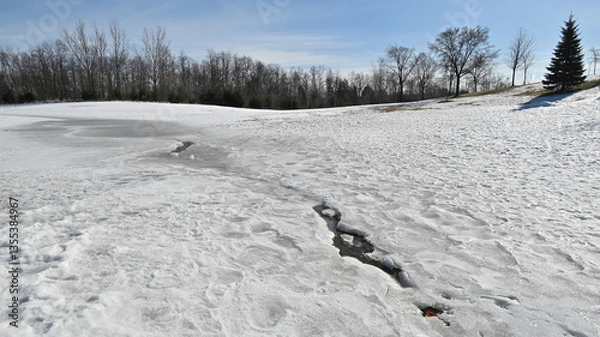 Fototapeta Dramatic wide-angle view of  breaking up of ice surface in the park.