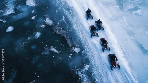 Fototapeta Aerial view of snowmobiles traversing frozen terrain in extreme winter conditions