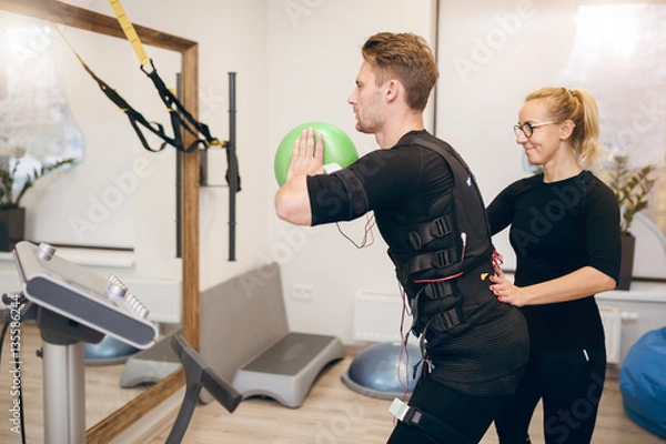 Fototapeta Sportsman doing ems training with coach in front of mirror