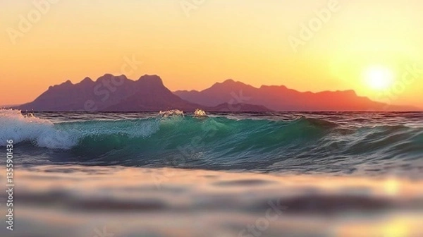 Fototapeta Ocean wave crashes on shore at sunset, with mountains in the background