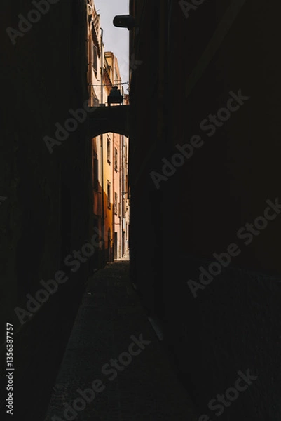 Obraz Dark narrow passage between buildings with a sunny street in the end