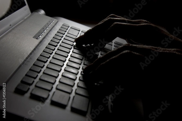 Fototapeta Hacker is up to something in a dark room.