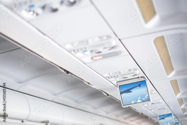 Obraz Control and information elements for passenger in white interior of modern aircraft, White interior space airliner, Display interior airliner, Advertising displays in aircraft interior