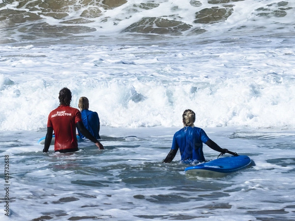 Obraz A couple of two surfers with their boards trying to get out trou