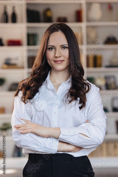 Fototapeta Confident young businesswoman with crossed arms in modern office interior