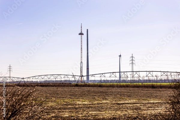 Fototapeta A wind turbine under construction stands next to a fully assembled one, symbolizing progress in renewable energy. The scene captures the transition to sustainable power as the nacelle is being lifted 