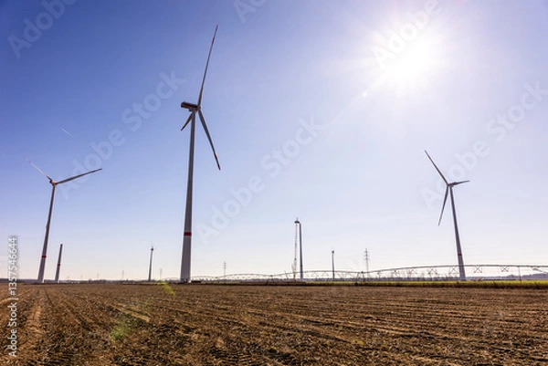 Fototapeta A wind turbine under construction stands next to a fully assembled one, symbolizing progress in renewable energy. The scene captures the transition to sustainable power as the nacelle is being lifted 