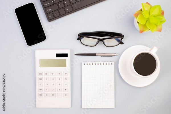 Fototapeta Tablet, calculator, phone, pen and a cup of coffee, lot of things on a light background. Top view with copy space.