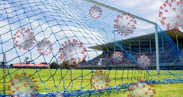 Obraz Image of 3d coronavirus cells floating over soccer player kicking ball on empty stadium