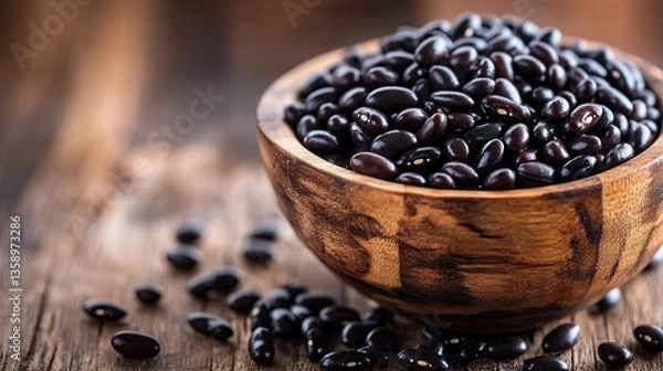 Fototapeta A wooden bowl filled with glossy black beans soaking in water overnight.