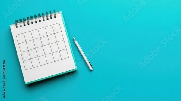 Fototapeta Productivity Tools calendar concept. Blank calendar notebook with a pen on a blue background.
