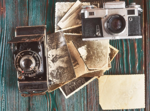Fototapeta Three generations of a photo cameras and old photos on memory. Ancient authentic wooden background