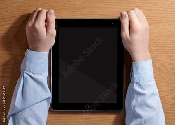 Fototapeta Boy holding a tablet PC sitting at the table. Top view.