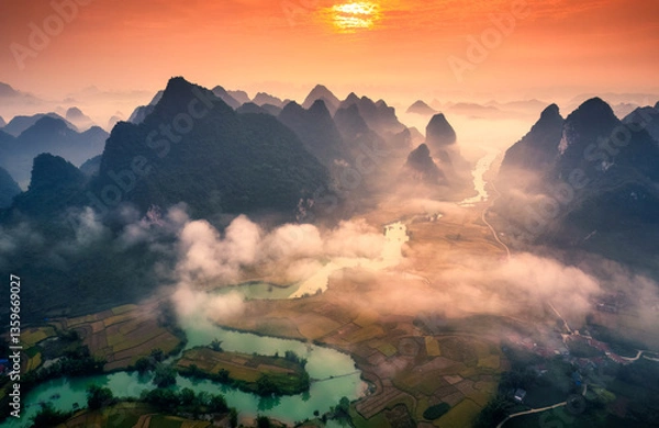 Fototapeta Sunrise over mountain range with foggy on rural village and river flows through in Phong Nam Valley at Vietnam