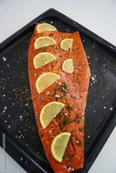 Fototapeta A whole red salmon filet with lemon and herbs