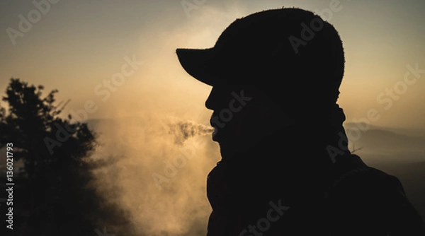 Fototapeta silhouette of a guy producing a cloud of smoke from a vaporizer
