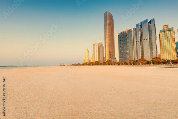Fototapeta Scenic view of Abu Dhabi Corniche beach during sunrise with modern skyscrapers rising majestically in the background