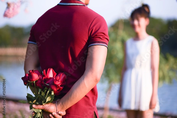 Obraz A young man hides behind a rose