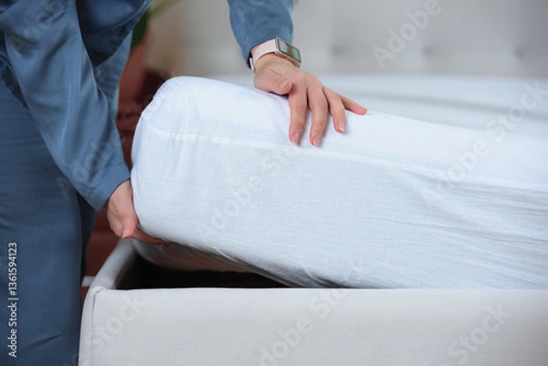Obraz Woman's hand puts a cover on the mattress to protect it from water and house dust mites