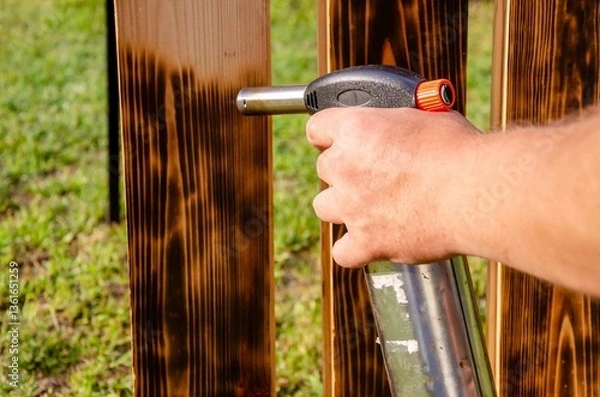 Obraz Treating wooden planks with fire from a gas cylinder.
