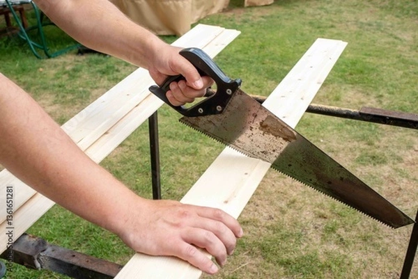 Obraz A saw in a man's hand saws a board.