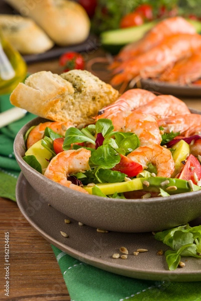 Obraz Spring salad with shrimp, mango and avocado. Served in a bowl, with croutons, sprinkled with roasted sunflower seeds.