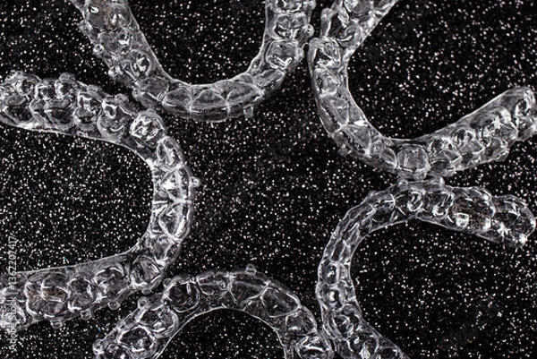 Obraz Invisible dental teeth brackets tooth aligners on black background. Plastic braces dentistry retainers to straighten teeth.