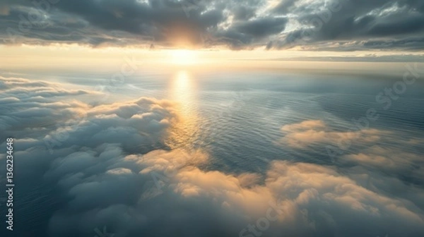 Fototapeta A breathtaking aerial view of the ocean at sunset, with clouds reflecting golden hues, creating a serene atmosphere