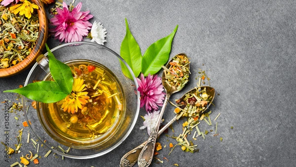 Fototapeta Composition with a Cup of healthy herbal tea and a set of dry tea and flowers. On a gray concrete background. Vertical photo.