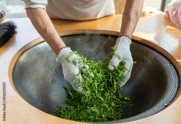 Obraz Traditional Chinese tea making techniques involve workers stir frying freshly picked green tea in iron pots