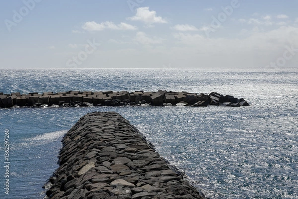 Obraz Black stone piers in the Atlantic Ocean with reflected sunlight and glare