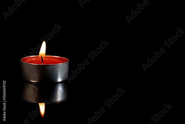 Obraz A burning scented candle against a black background