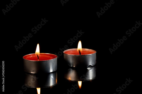 Obraz Two burning candles on black background