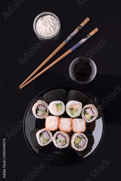 Fototapeta Sushi set with soy sauce, mayonnaise and chopsticks on black background