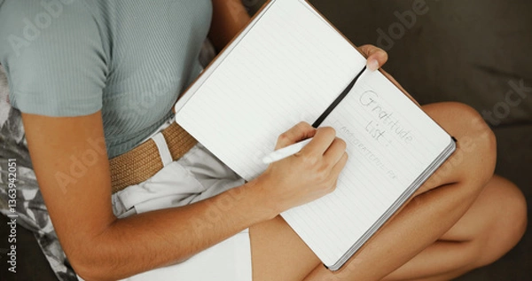 Fototapeta Writing, notebook and gratitude with hands of woman on sofa for inspiration, self care journal and reflection. Reminder checklist, mental health prompt and relax with person in living room of home