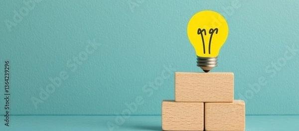 Fototapeta Bright Yellow Light Bulb on Wooden Blocks Against Turquoise Background as a Symbol of Creativity and Innovation