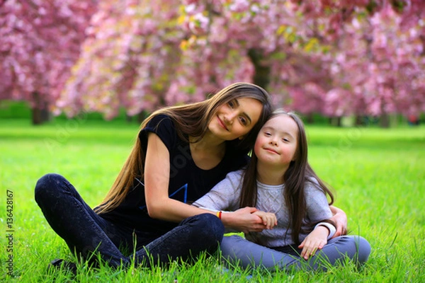 Obraz Happy beautiful young woman with girl in blossom park with trees and flowers.