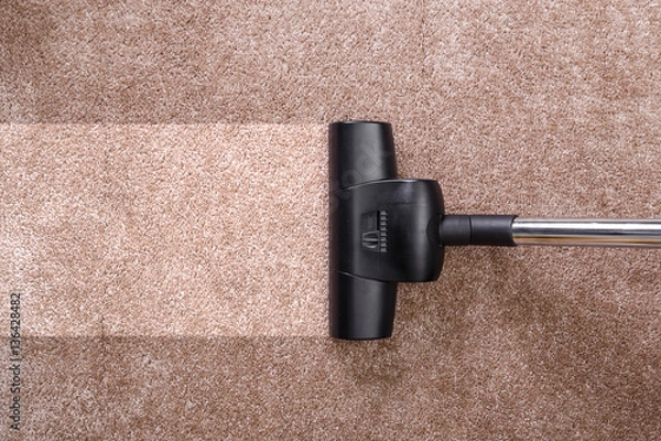 Fototapeta Vacuuming carpet with vacuum cleaner. Housework service. Close up of the head of a sweeper cleaning device.