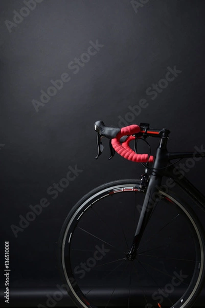 Fototapeta red handlebar and black wheel of a race bicycle on black backgro