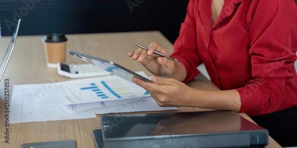 Fototapeta Review and Evaluation. A professional analyzing charts on a tablet to enhance financial understanding and decisions.