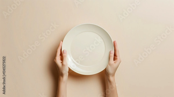 Obraz A person is holding a plate with a white rim. The plate is empty and the person is holding it up to the camera. Concept of emptiness and simplicity