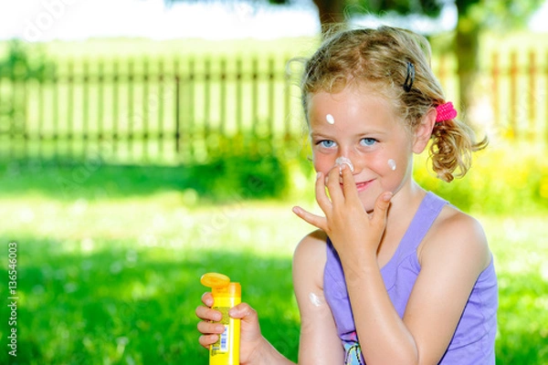 Obraz blond girl using sun cream in garden