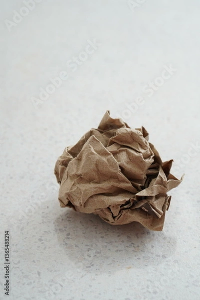 Fototapeta Crumpled piece of craft paper into a ball on a light background