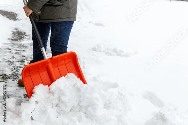 Fototapeta Woman with shovel cleaning snow. Winter shoveling. Removing snow after blizzard.