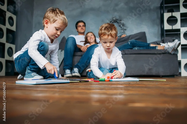 Fototapeta Children draw markers on floor while parents relax couch