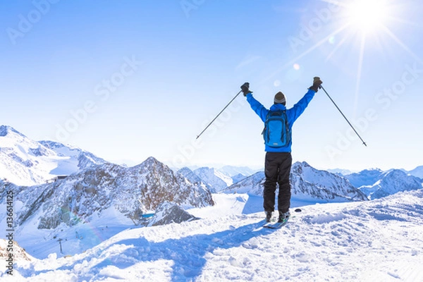 Fototapeta Back view of a happy skier with raised hands