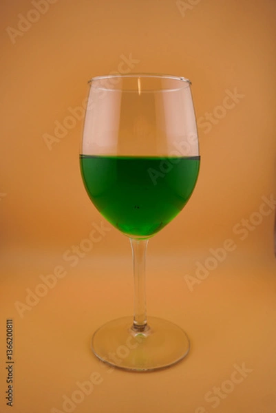 Fototapeta Colored water dropping into a wine glass filled with water.