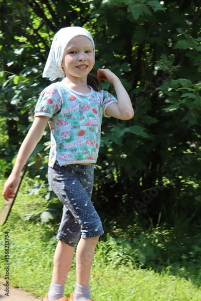 Obraz little girl is walking in the village. child is hopping on the road. countryside scene.